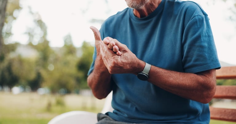 Senior, man and hands with injury, pain or ache for fibromyalgia or muscle tension on park bench. Closeup, male person or carpal tunnel syndrome with sore fingers, joint inflammation or cramps