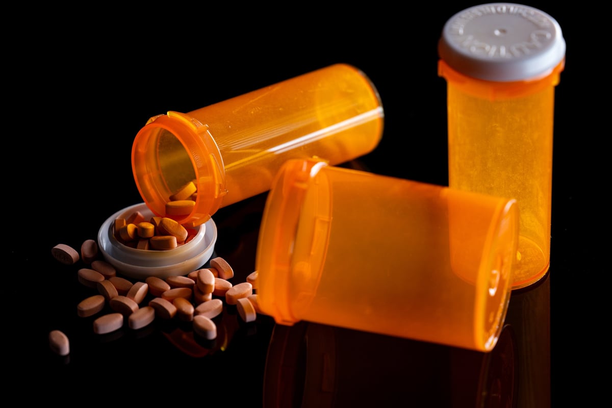 Pills and open prescriptions bottles on a black background as a healthcare concept.